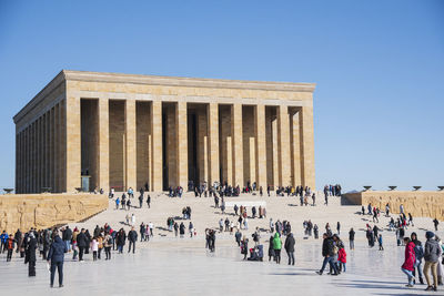 Group of people walking on street against clear blue sky