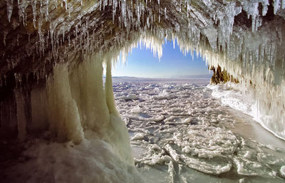 Frozen cave against sky