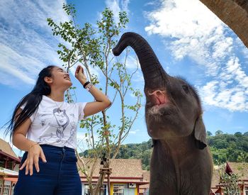 Woman with elephant standing against sky