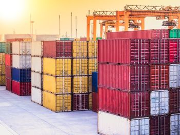 Stack of multi colored cargo containers at harbor against sky