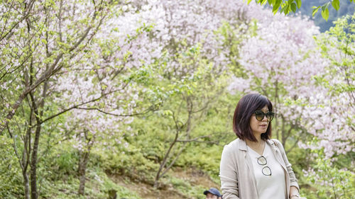 Young woman standing against trees