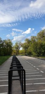 Empty road by trees against sky