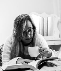 Portrait of young woman reading book at home