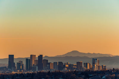 Buildings in city against clear sky during sunset