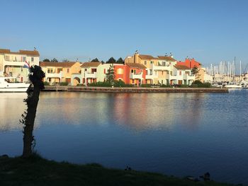 Buildings by river against blue sky