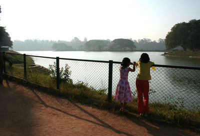 Rear view of women standing on water against sky