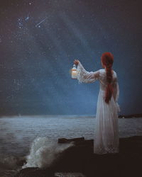 Digital composite image of woman standing by sea against sky