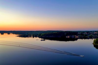 Sunset reflected on the lake, moon rising and boat ripping the still waters