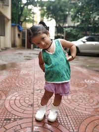 Portrait of cute baby girl standing on footpath