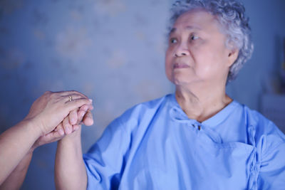 Cropped image holding patient hand against wall