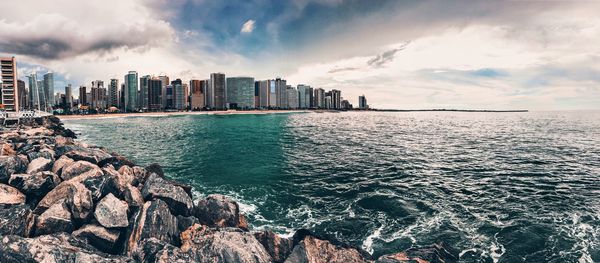 Panoramic view of sea and buildings against sky