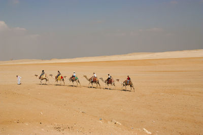 People in desert against sky