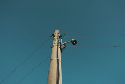 Low angle view of telephone pole against clear blue sky