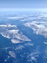 Aerial view of sea and snowcapped mountains against sky