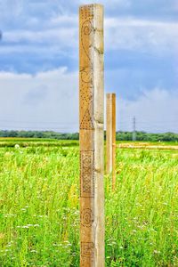 Close-up of wooden post on field against sky