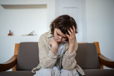 Young woman using mobile phone while sitting at home