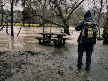 Rear view of man on snow covered landscape during rainy season