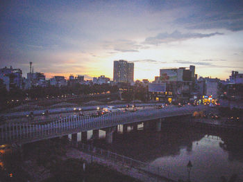 View of city at waterfront against cloudy sky