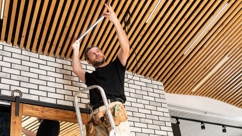 Low angle view of man repairing ceiling