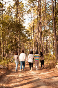 Rear view of people or woman friend walking in forest