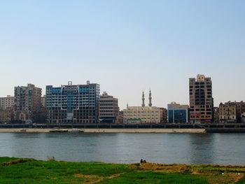 River by buildings against clear sky