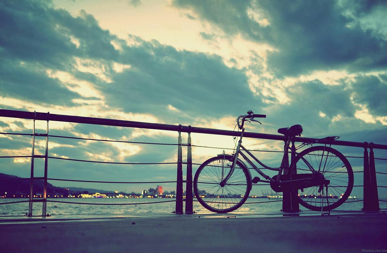 transportation, sky, mode of transport, cloud - sky, bicycle, land vehicle, cloudy, cloud, stationary, parking, railing, parked, built structure, travel, architecture, sunset, road, outdoors, day, no people