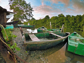 Abandoned boat moored in water against sky