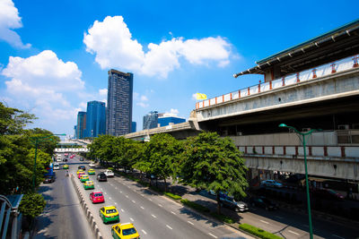 Cars on road by buildings in city against sky