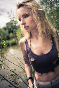 Thoughtful beautiful woman looking away while standing against plants