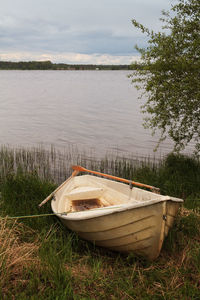 Boat moored by lake against sky