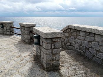 Stone wall by sea against sky