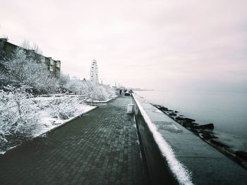 Road by sea against sky during winter