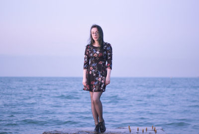 Woman standing at beach against sky