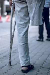 Low section of disabled man standing on footpath in city