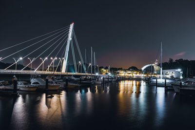 Illuminated bridge over river against sky at night