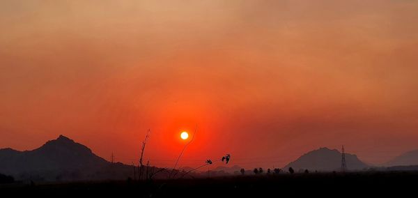 Scenic view of silhouette mountains against orange sky