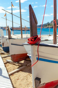 Sailboat moored on wooden post at beach against sky