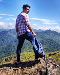 Full length of young man on rock against sky