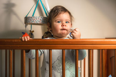 Portrait of cute boy with pacifier by railing at home