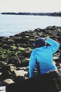 Rear view of man overlooking sea against sky