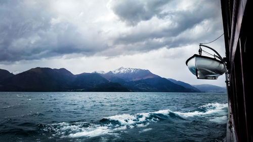 Sailboat in sea against mountains