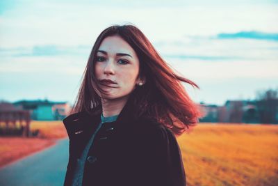 Portrait of beautiful young woman standing against sky