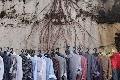 Shirts hanging on clothesline for sale against wall