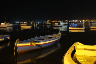 Boats moored in harbor at night