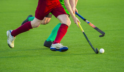 Low section of players playing hockey on field