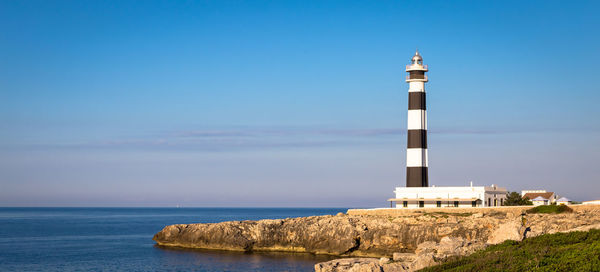 Lighthouse by sea against sky