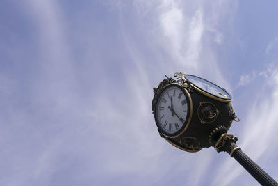 Low angle view of clock against sky