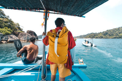 Rear view of men standing on boat in sea