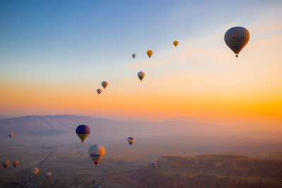 Hot air balloons flying against sky during sunset