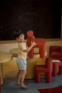 Full length of cute boy playing with chairs